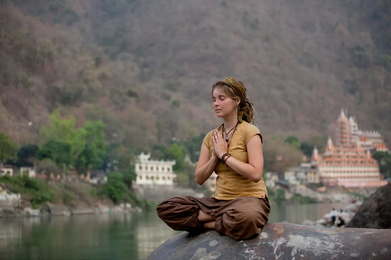 woman meditating on the banks of Ganges River Rishikesh